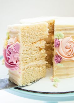 a white cake with pink and yellow frosting on a plate next to a knife