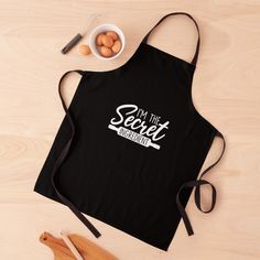 a black apron with the word curious on it next to eggs and utensils