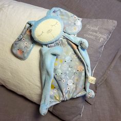 a blue stuffed animal laying on top of a pillow