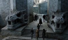 some people are standing in front of stairs and stone buildings with dragon heads on them