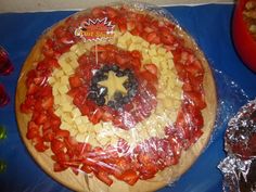 a captain america themed pizza on a blue tablecloth with other foods and condiments