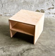 a small wooden table sitting on top of a cement floor next to a stone wall