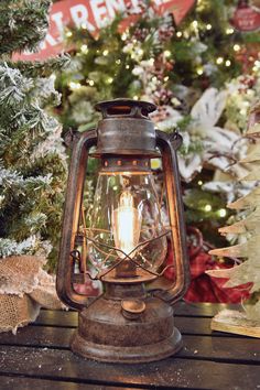 an old fashioned lantern sits in front of a christmas tree