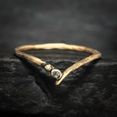 a close up of a gold ring on top of a rock with a diamond in the middle