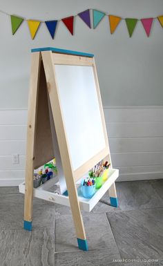 a child's wooden easel with paint and markers on it