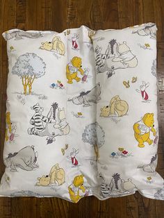 two pillows with winnie the pooh characters on them sitting on a wooden floor next to each other