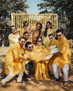 a group of men and women posing for a photo together in yellow outfits with sunglasses on