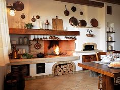 a kitchen with a table, oven and shelves filled with pots and pans on the wall