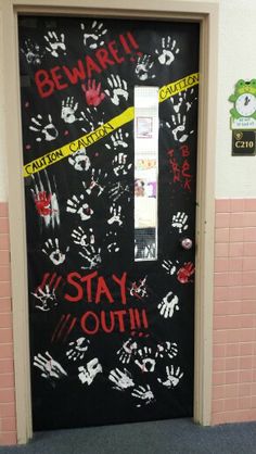 a door decorated with handprints and caution tape that reads beware i stay out