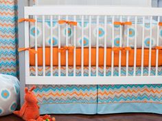 a baby crib with blue, orange and white bedding