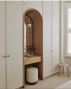 a room with white cupboards and a mirror on the wall next to a stool