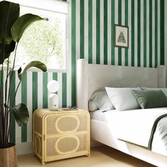 a bedroom with green and white stripes on the walls, bedding and nightstands