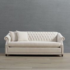 a white couch sitting on top of a wooden floor next to a wall with gray walls