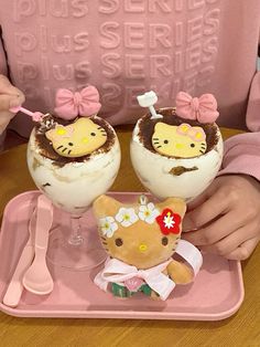 two hello kitty desserts are sitting on a pink tray