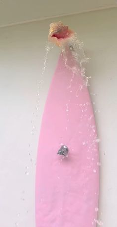 a pink surfboard is being splashed with water