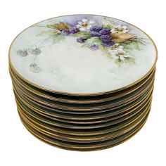 a stack of gold and white plates with purple flowers on the rim, all stacked up