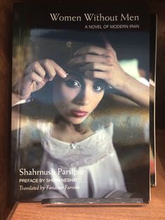 a woman without men book sitting on top of a wooden shelf