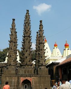 people are walking around in front of an old building with many spires on it