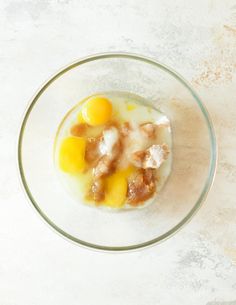 a glass bowl filled with food on top of a white countertop next to a knife and fork