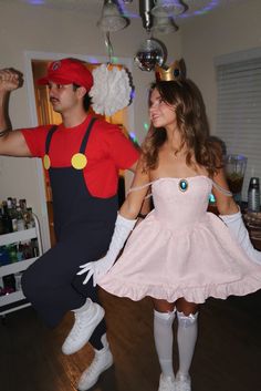 a man and woman dressed up as mario and luigi are dancing in the living room