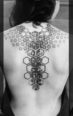 the back of a woman's body with geometric tattoos on her upper and shoulder