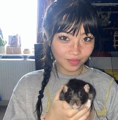 a woman holding a small rodent in her hands