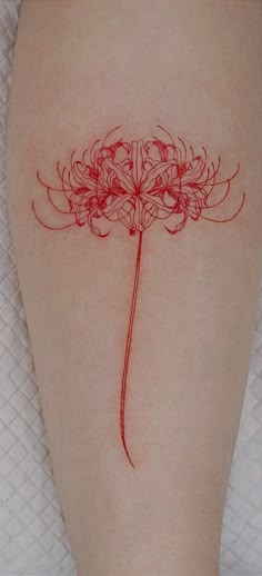 a woman's leg with a tattoo on it that has red ink and flowers