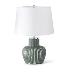 a table lamp with a white shade on the base and a green striped ceramic vase