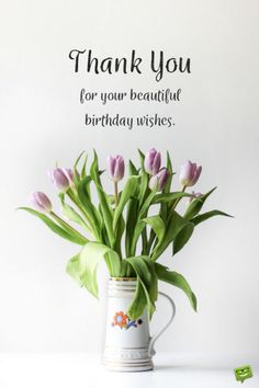 a vase filled with purple tulips sitting on top of a table next to a sign