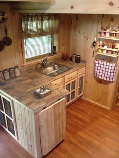 a kitchen with wooden walls and flooring next to a window