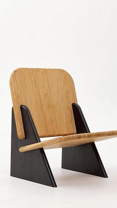 a wooden chair sitting on top of a white floor next to a black stand with a wooden stick sticking out of it