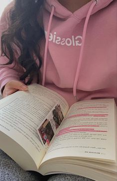 a girl in a pink hoodie reading a book