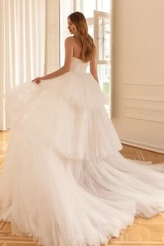 a woman in a white wedding dress is standing on the floor with her back to the camera