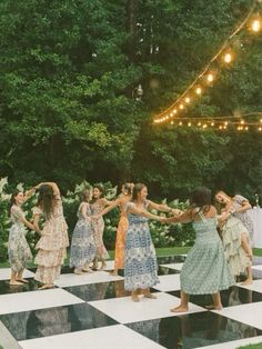 a group of women standing on top of a checkered floor in front of trees