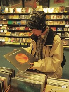 a man in headphones is looking through cds at a record store shelf with records on the shelves