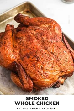 a roasted whole chicken on a baking sheet with the words smoked whole chicken written below