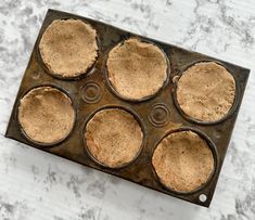 a muffin pan filled with cupcakes sitting on top of a marble counter