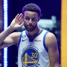 the golden state warriors player is holding his hand up to his ear and looking at the camera