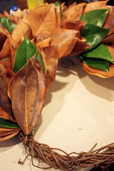 a wreath made out of leaves and twigs on a table with other items in the background