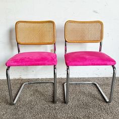 two pink chairs sitting next to each other on carpeted floor in front of white wall