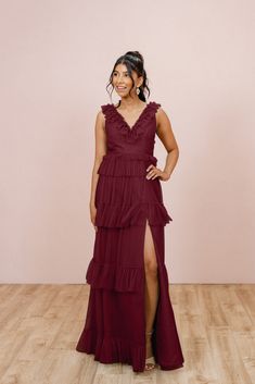 a woman in a red dress standing on a wooden floor with her hands on her hips