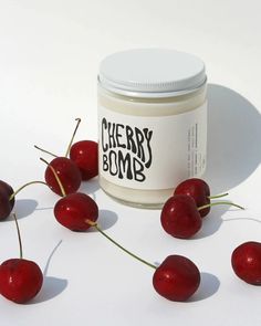 some cherries and a jar of cherry bomb on a white surface with the words cherry bomb