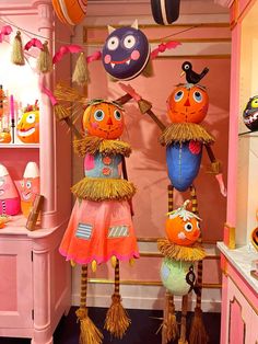 three scarecrows are hanging from the ceiling in front of a pink wall and shelves