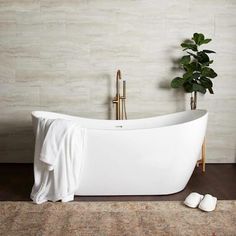 a white bathtub sitting on top of a wooden floor next to a potted plant