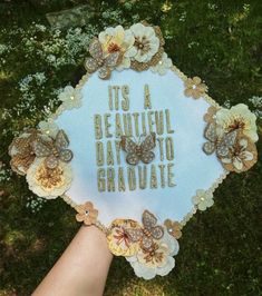 a hand holding a sign that says it's a beautiful day to graduate with butterflies on it