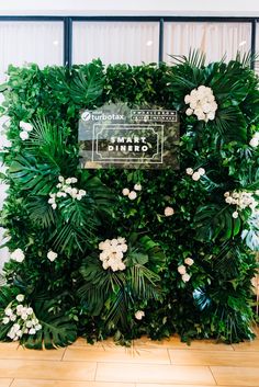 an artificial plant wall with white flowers and greenery on the top, along with a sign that says private dining