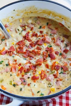 a white bowl filled with ham and cheese soup on top of a checkered table cloth