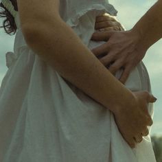 a woman in a white dress holding her hands together