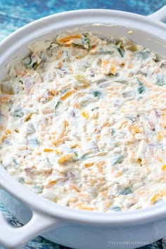 a casserole dish with cheese and vegetables in it on a blue tablecloth