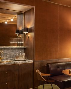 a room with wooden paneling and marble counter tops, along with brown leather couches